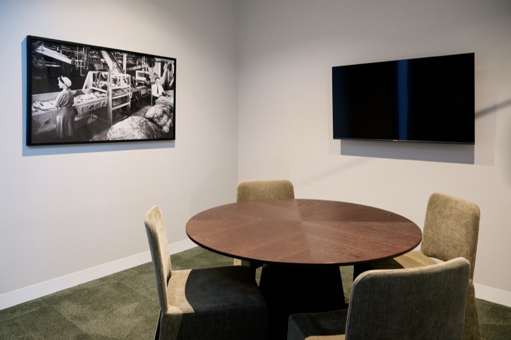 Meeting Room 2 with a round timber table, four chairs and a wall-mounted screen